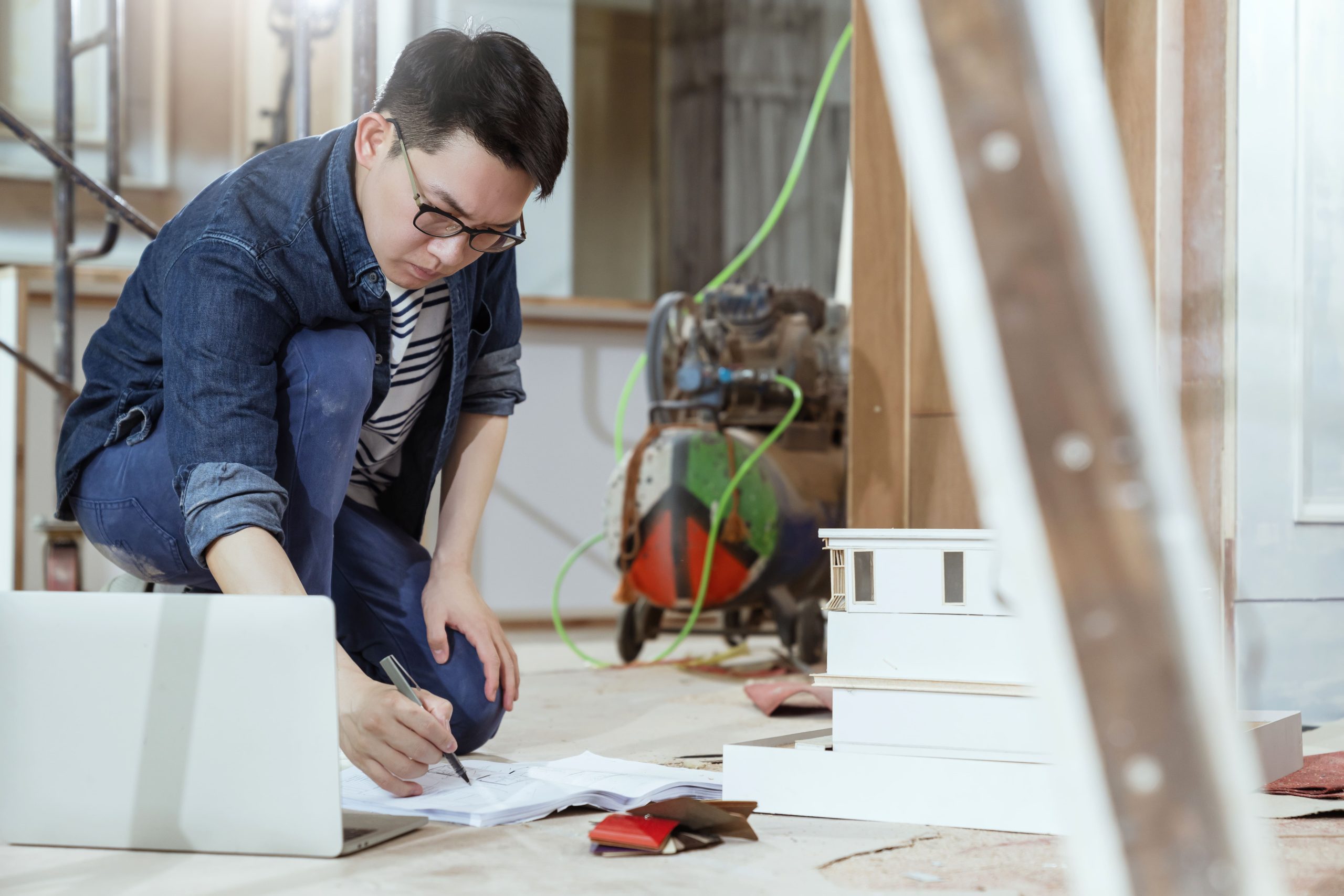 portrait-young-asian-contractor-carpenter-site-checking-blueprint-floor-with-concentrate-focus-home-renovate-site-construction-background
